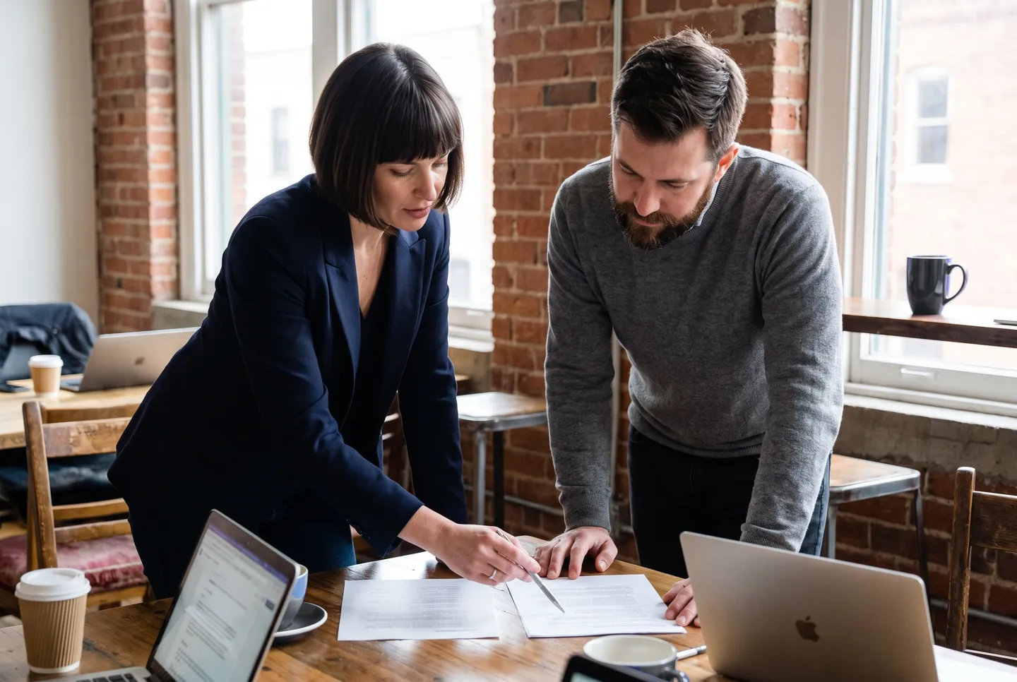 Двоє засновників нахиляються над столом і порівнюють два аркуші паперу